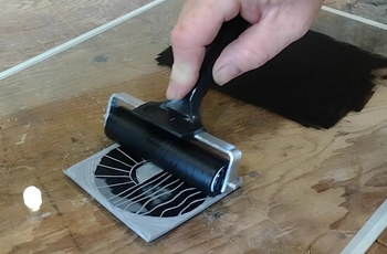 Using a brayer to spread the ink onto the design.
