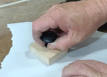Using a homemade baren to rub the paper into the ink.