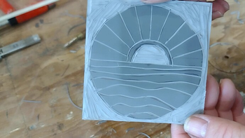 Showing the final carved design in the linoleum. It is a stylized sunset over water.